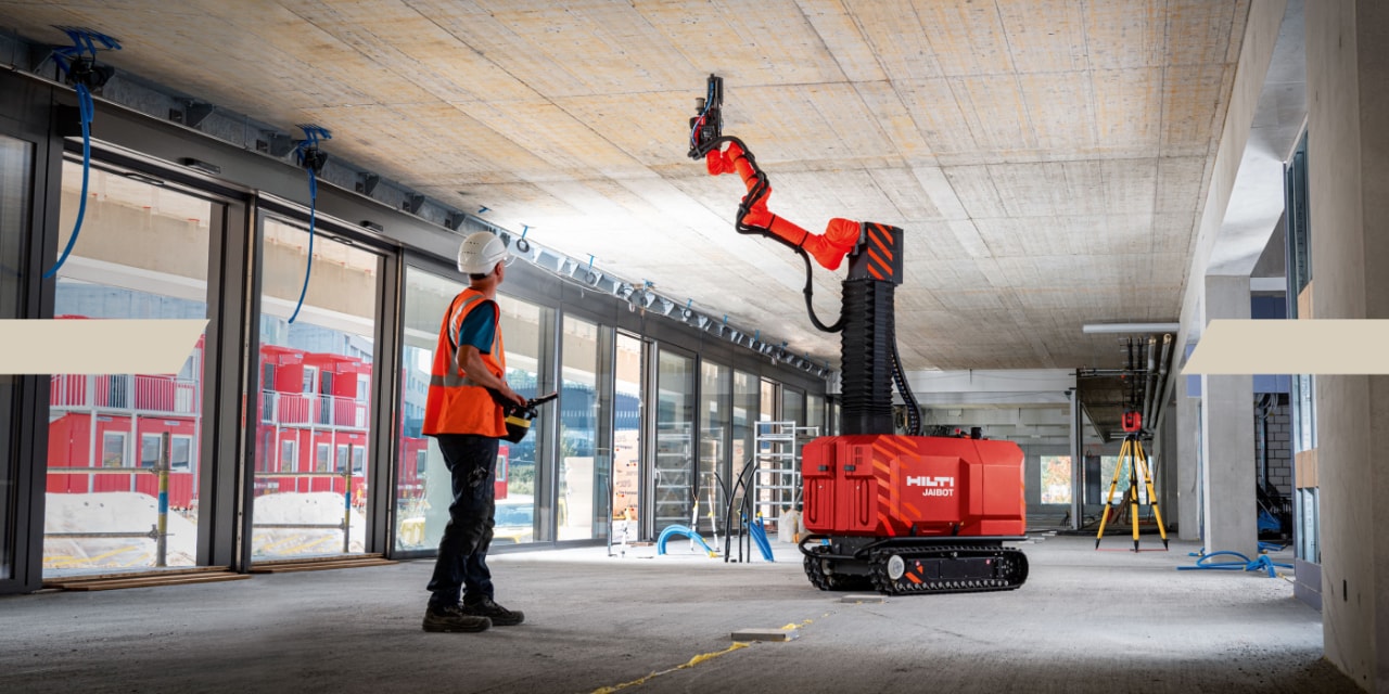 Een man vraagt ​​de Hilti Jaibot om aan het plafond te werken door deze via een afstandsbediening te bedienen.