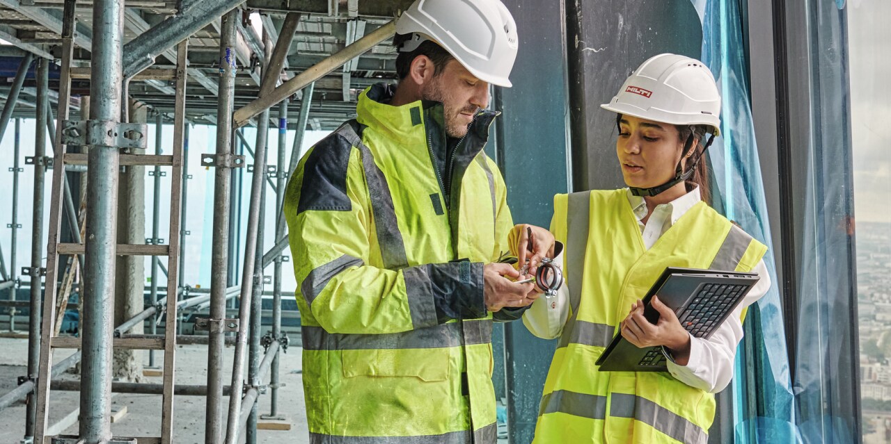 Accountmanager praat met een klant op de bouwplaats en toont hem het MEP-assortiment verbruiksmaterialen