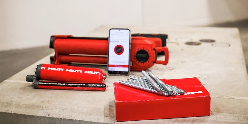 Een foto toont de app voor volumeberekening, de HIT HY 200-A V3 injectiemortel, de HDE 500-22 en ankerstangen