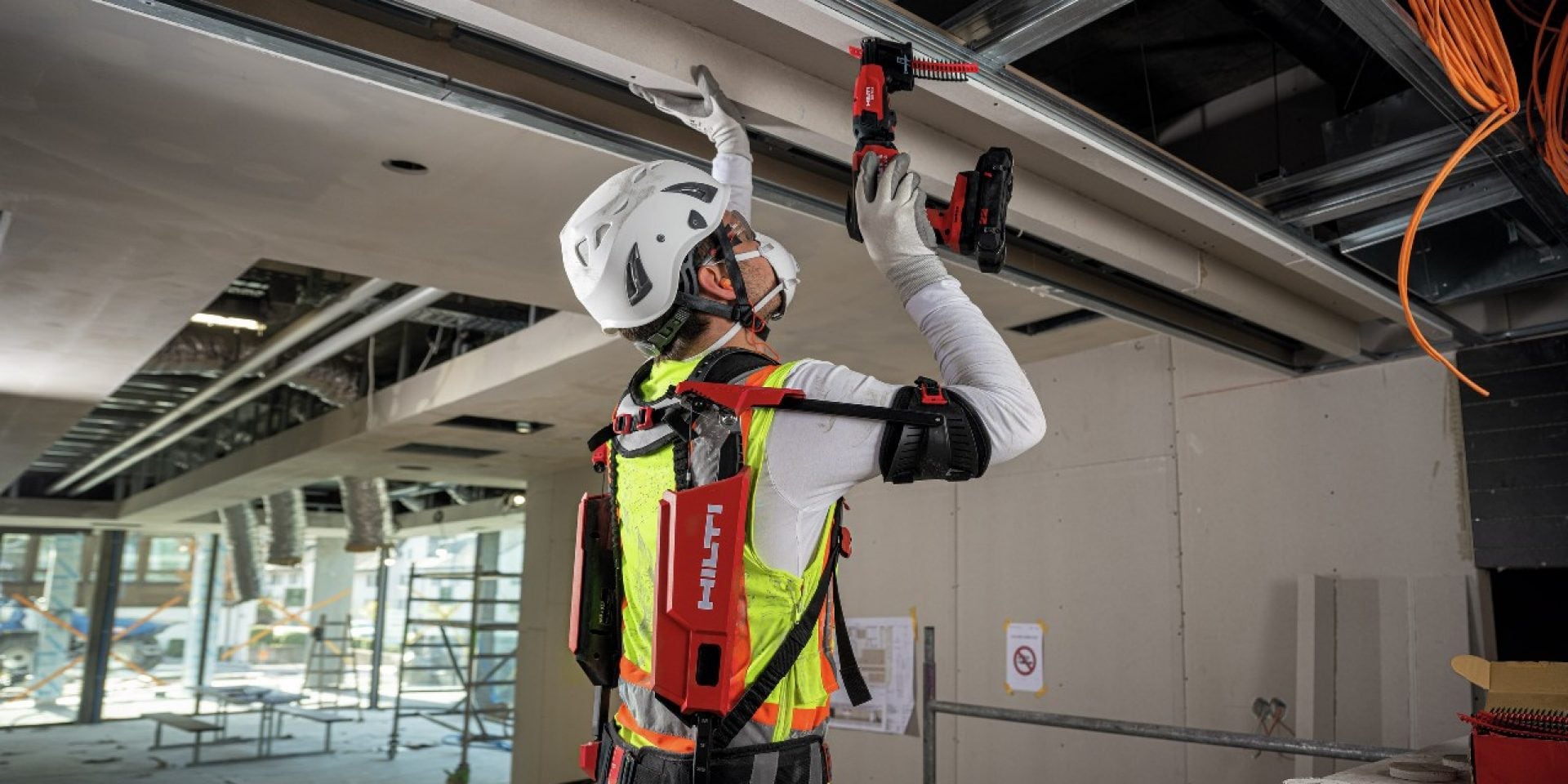 Een persoon met een Hilti exo-skelet werkt boven zijn hoofd.